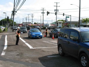 Special-duty police officers direct traffic at the busy intersection of Kilauea Avenue and Pauahi Street Friday afternoon. Motorists are being advised to avoid the area this weekend as the repaving work will continue Saturday and Sunday. Photo by Dave Smith.