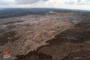 This photo, taken Feb. 23 at 6 p.m., shows a large flow (lighter colored area), approximately 1/4 mile long, that had erupted from a point between Pu‘u ‘O‘o and the perched pond, covering a large portion of the north flank. And, while most of the flow had crusted over, several large rivers of lava were still visible, and many little hotspots existed. Photo credit: Extreme Exposure Media/Paradise Helicopters.