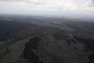 The March 9 breakouts, which issued from the vicinity of Puʻu Kahaualeʻa, are advancing northward (to the left) and reached the forest at the north edge of the Kahaualeʻa flows and was burning vegetation along its edges on March 17 when this photo was taken. USGS HVO photo.