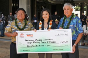 Contest winner Haruna Yamanaka (center) was presented with a $500 check by Glenn Inouye of Servco Pacific (right) and HDOT Deputy Director Jade Butay (left) during Tuesday's event. Her winning concept and script will be professionally produced and broadcast on television and in movie theaters statewide over the summer. HDOT photo. 