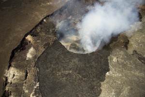 July 23: This photograph shows overflows from April and May (dark lava in bottom portion of photograph) covering the floor of Halemaʻumaʻu Crater. USGS/HVO photo.