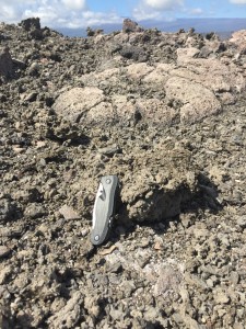 The 10 cm (4-inch) pocket knife in this image provides scale for one of the larger fragments of molten lava that was thrown onto the rim of Halemaʻumaʻu Crater during the Jan. 8 event. HVO photo.