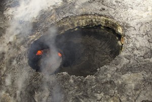 In the western portion of Puʻu ʻŌʻō Crater, there has been a small pit for nearly a year. The pit is about 60 m (200 feet) wide, and a small circular lava pond resides beneath the overhanging west rim of this pit. USGS/HVO photo.