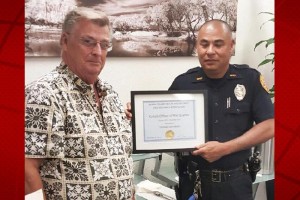 Hawaiʻi Island Security and Safety Professionals Association board member William King presents a 'Kohala Officer of the Quarter' award to Officer Thomas Koyanagi. HPD photo.