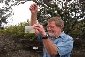 During a 2015 field trip with Franklin and Marshall College students, Don Swanson, a geologist at the USGS Hawaiian Volcano Observatory, demonstrates that reticulite (frothy basalt, less dense than pumice, explosively erupted in lava fountains) sinks, rather than floats, in water due to its high permeability. Swanson is the recipient of two prestigious awards honoring his career as a research volcanologist and science communicator. USGS/HVO photo.