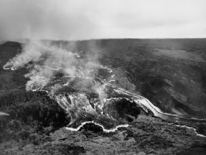 This rapidly moving ʻaʻā lava flow was one of several that advanced down the west flank of Mauna Loa during the volcano’s 1950 eruption. The massive flow, tens of meters (yards) high, traveled from the Southwest Rift Zone vent to the ocean, a distance of about 18 km (11 miles) in around 18 hours. Two earlier flows from this eruption reached the ocean in as little as three hours. All three flows crossed Highway 11 as they advanced to the sea. In this black-and-white aerial photo, incandescently hot areas on the flow appear white. Photo credit: Air National Guard, 199th Fighter Squadron.