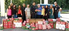 HPD Chief Harry Kubojiri presents 136 shoeboxes full of Christmas presents donated by police department personnel to Nell Quay, Operation Christmas Child area coordinator of East Hawai‘i. To the chief's left is Steve Meek, the island's collections coordinator for the charity project.